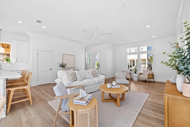 living room featuring light wood-type flooring, a healthy amount of sunlight, visible vents, and baseboards