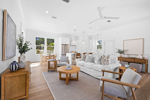 living room featuring crown molding, light hardwood / wood-style flooring, and ceiling fan