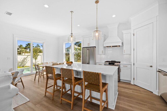 kitchen with decorative light fixtures, light hardwood / wood-style floors, stainless steel appliances, white cabinetry, and custom exhaust hood