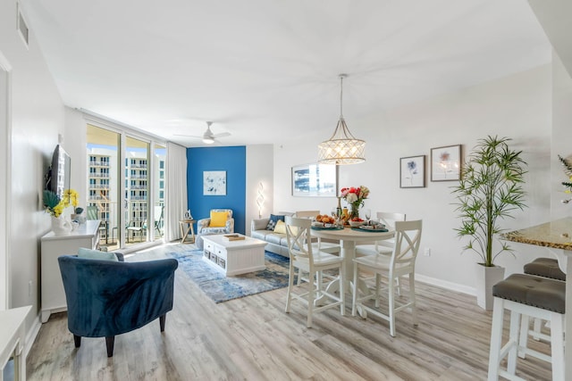 living room featuring ceiling fan with notable chandelier and light hardwood / wood-style floors