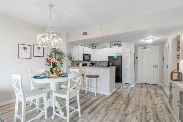 kitchen with white cabinets, backsplash, light hardwood / wood-style floors, black appliances, and kitchen peninsula