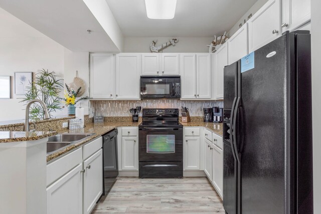 kitchen with white cabinetry, black appliances, light hardwood / wood-style flooring, and stone countertops