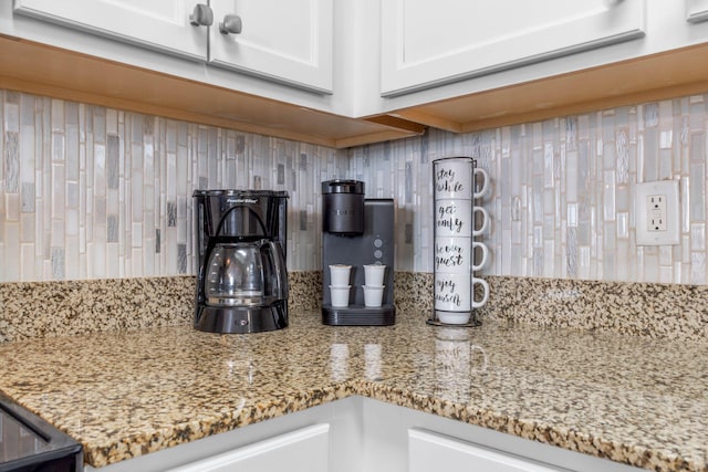 interior details with light stone counters, backsplash, and white cabinets