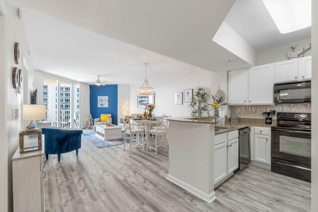 kitchen with white cabinets, light wood-type flooring, black appliances, kitchen peninsula, and tasteful backsplash