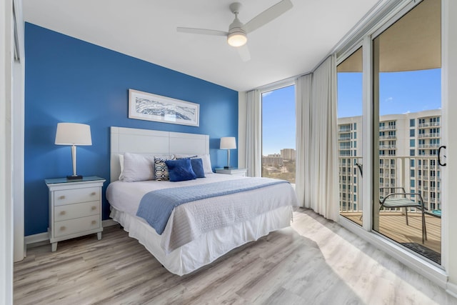 bedroom featuring light wood-type flooring, ceiling fan, and expansive windows