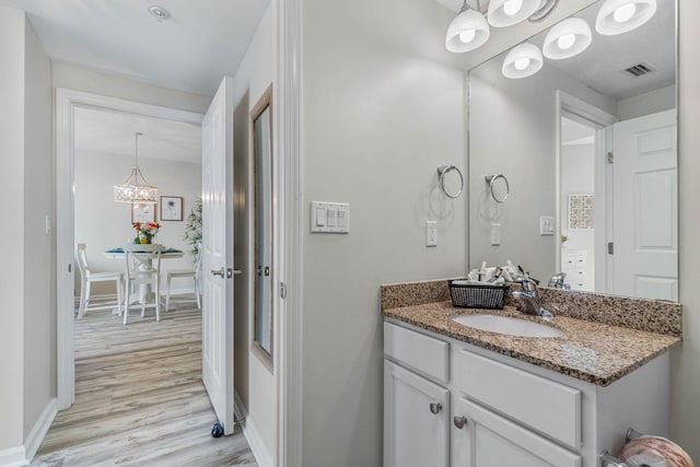 bathroom featuring wood-type flooring, a chandelier, and vanity