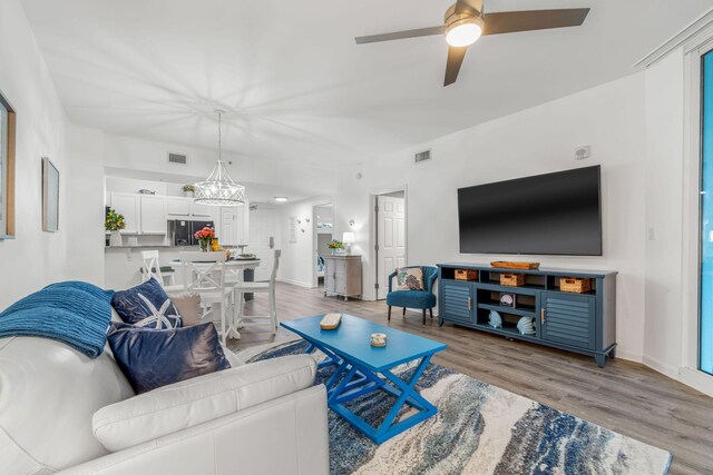 living room featuring ceiling fan with notable chandelier and wood-type flooring