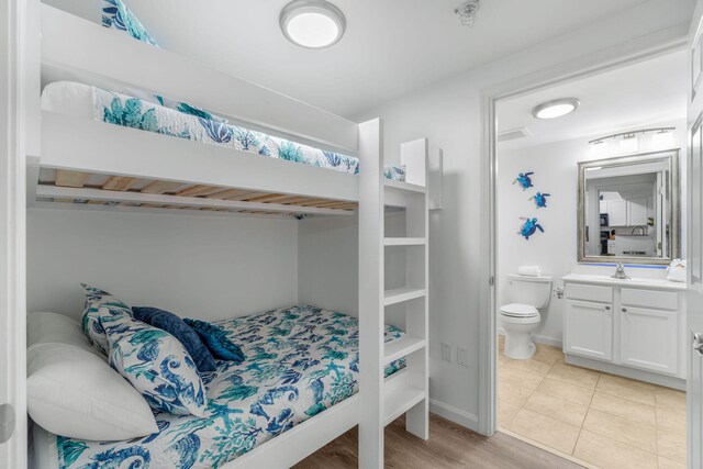 bedroom featuring light wood-type flooring and ensuite bath