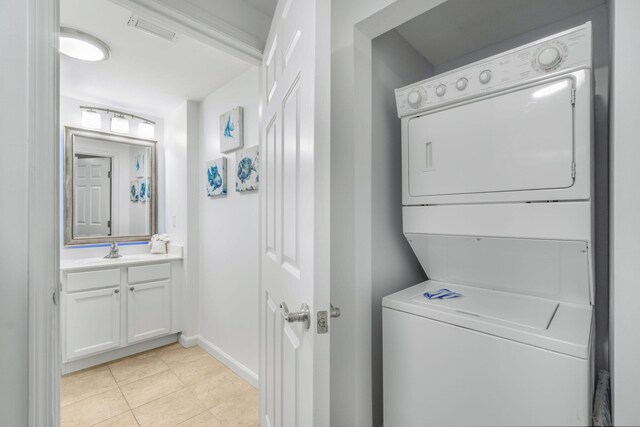 laundry room featuring stacked washer / dryer, light tile patterned floors, and sink