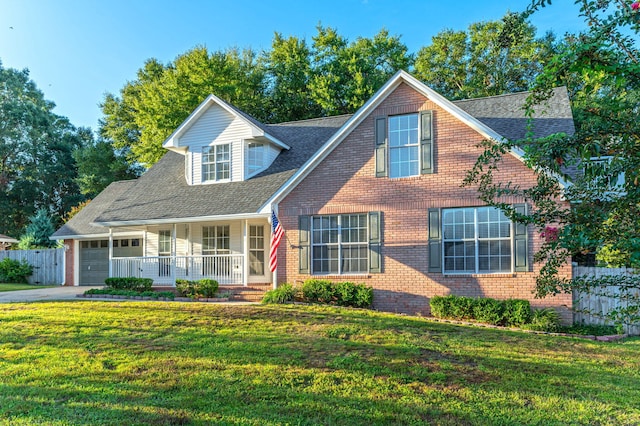 view of front of house featuring brick siding, covered porch, fence, driveway, and a front lawn