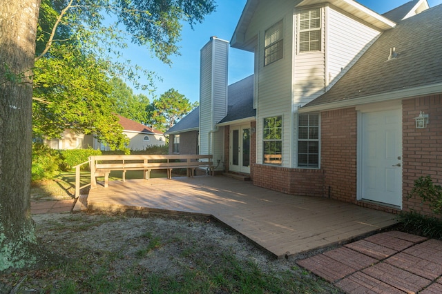 rear view of property featuring a shingled roof, a patio, a chimney, french doors, and brick siding