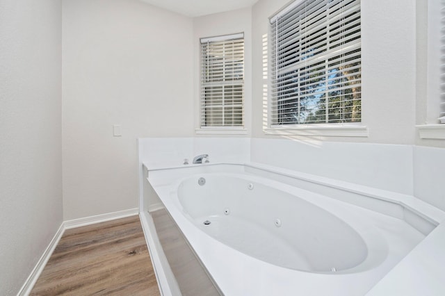 full bathroom with baseboards, a tub with jets, and wood finished floors