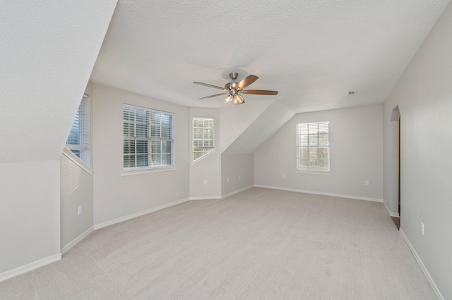 bonus room featuring baseboards, a ceiling fan, a textured ceiling, and light colored carpet