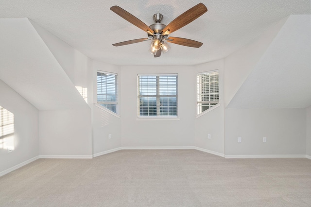 bonus room with light carpet, a textured ceiling, and baseboards