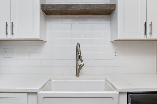 details with decorative backsplash, dishwashing machine, light stone counters, white cabinetry, and a sink