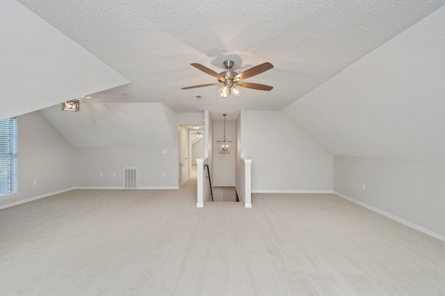 bonus room with lofted ceiling, visible vents, light carpet, a textured ceiling, and baseboards