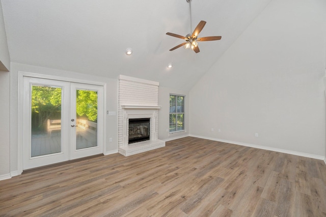 unfurnished living room featuring high vaulted ceiling, a fireplace, wood finished floors, and baseboards