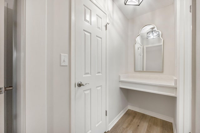 interior space with a textured ceiling, wood finished floors, and baseboards