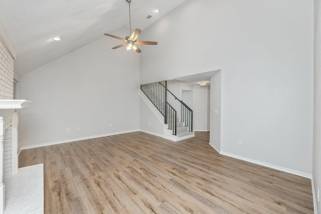 unfurnished living room with stairway, a fireplace, light wood-style flooring, and baseboards