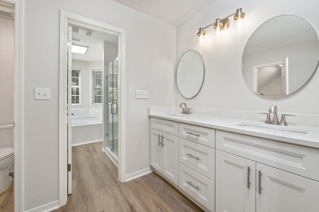 bathroom with toilet, a textured ceiling, a sink, and wood finished floors