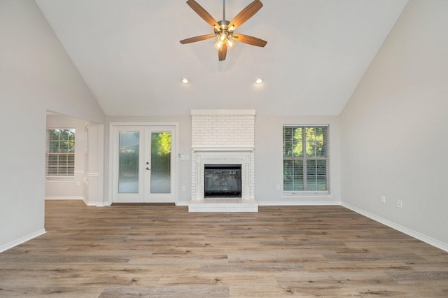 unfurnished living room featuring french doors, a brick fireplace, wood finished floors, and baseboards