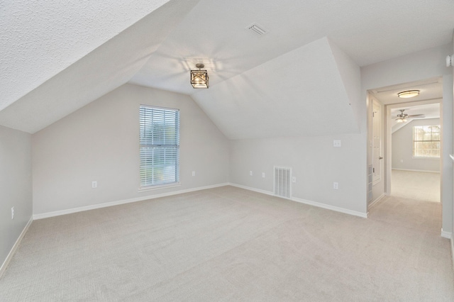 bonus room featuring light carpet, baseboards, visible vents, and lofted ceiling