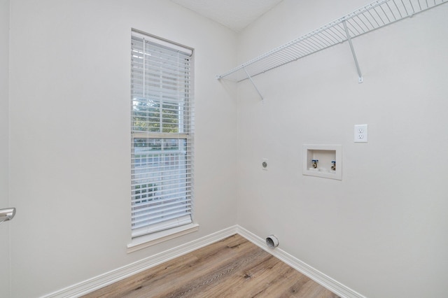 laundry area featuring hookup for a washing machine, laundry area, baseboards, light wood finished floors, and electric dryer hookup