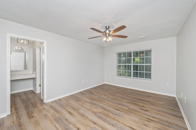 unfurnished bedroom featuring a textured ceiling, baseboards, and wood finished floors