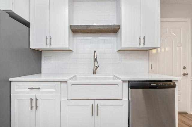 kitchen with light countertops, a sink, backsplash, and stainless steel dishwasher