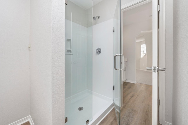 bathroom featuring a stall shower, wood finished floors, and baseboards