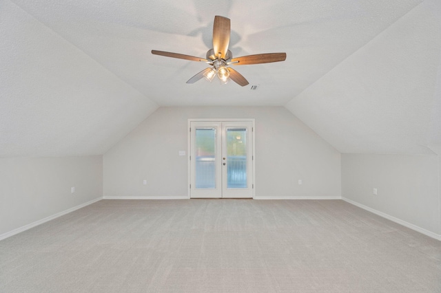 additional living space with lofted ceiling, light colored carpet, a ceiling fan, a textured ceiling, and baseboards