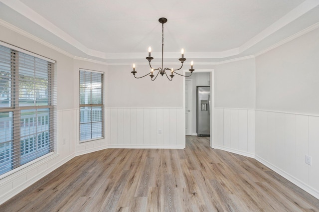 unfurnished dining area featuring a wainscoted wall, a raised ceiling, and wood finished floors