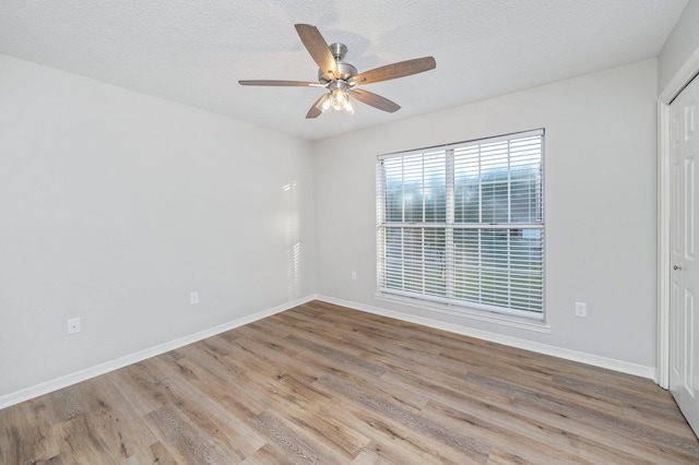 empty room with a textured ceiling, baseboards, and wood finished floors