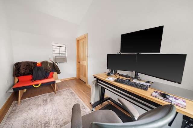 office space featuring vaulted ceiling, radiator, and light hardwood / wood-style flooring