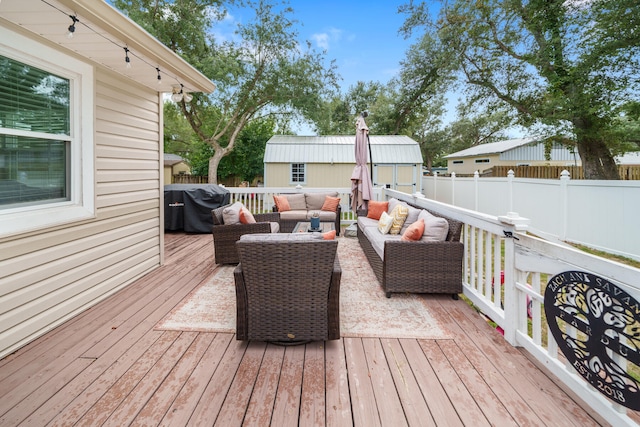 wooden terrace featuring a grill, an outdoor living space, and a shed