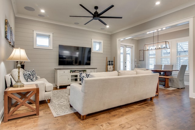 living room with a healthy amount of sunlight, ceiling fan with notable chandelier, and light hardwood / wood-style floors