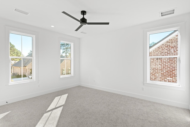 carpeted spare room with a wealth of natural light and ceiling fan