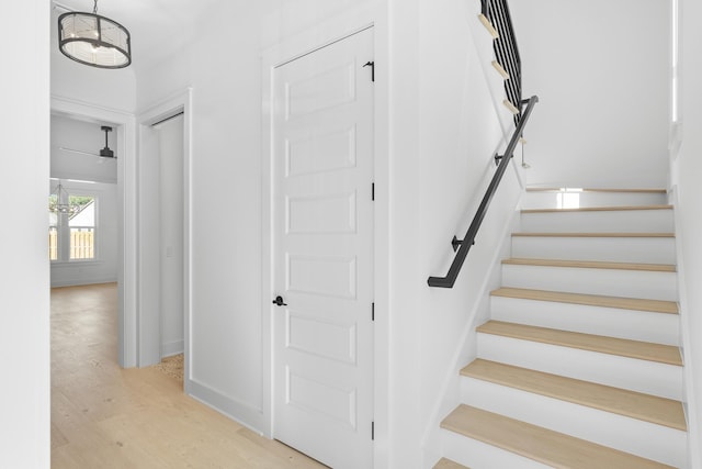 stairs with hardwood / wood-style floors and an inviting chandelier