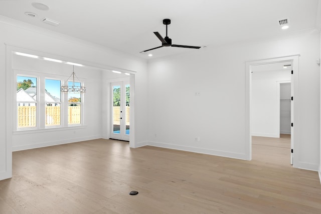 spare room featuring ceiling fan with notable chandelier, ornamental molding, and light hardwood / wood-style flooring