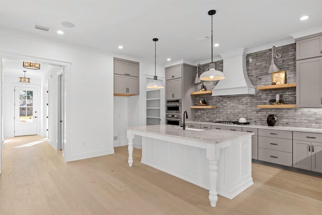 kitchen with a kitchen bar, appliances with stainless steel finishes, decorative backsplash, premium range hood, and a kitchen island with sink