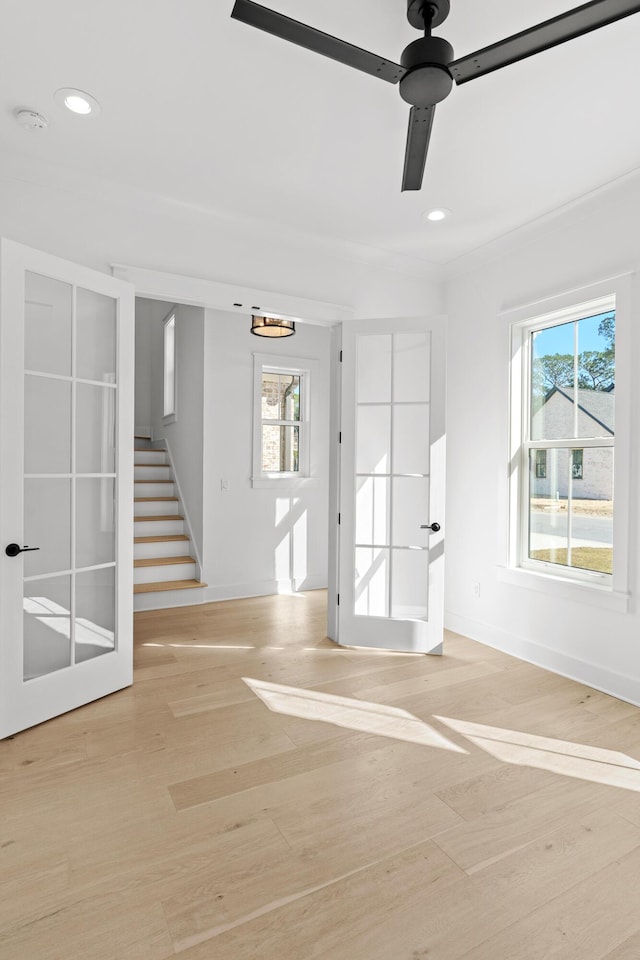 empty room featuring french doors, light wood-type flooring, and ceiling fan