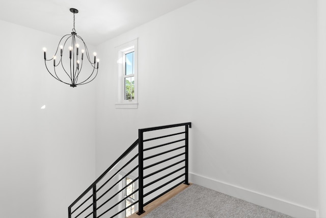 stairway with carpet flooring and an inviting chandelier