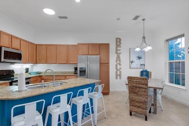 kitchen featuring appliances with stainless steel finishes, light stone counters, sink, pendant lighting, and tasteful backsplash