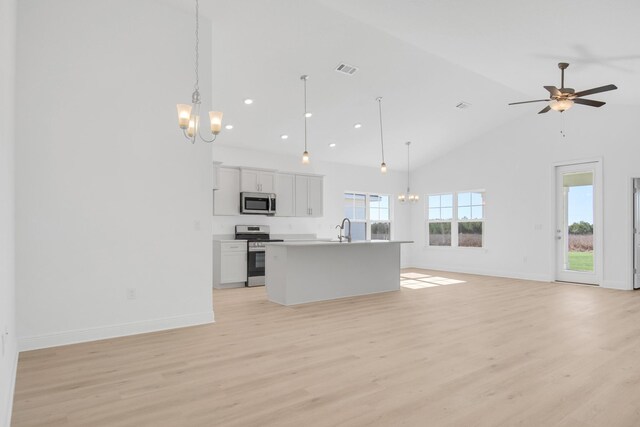 kitchen with ceiling fan with notable chandelier, appliances with stainless steel finishes, a kitchen island with sink, hanging light fixtures, and white cabinets