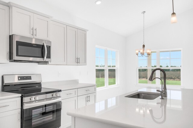 kitchen featuring an inviting chandelier, decorative light fixtures, stainless steel appliances, sink, and white cabinetry