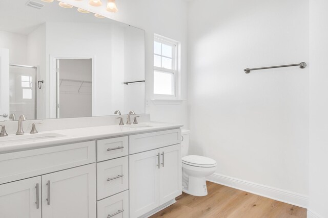 bathroom featuring vanity, toilet, hardwood / wood-style flooring, and a shower with shower door