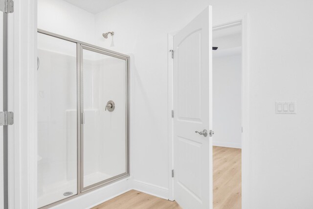 bathroom with hardwood / wood-style floors and an enclosed shower