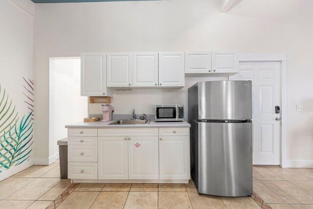 kitchen featuring light tile patterned floors, stainless steel appliances, white cabinetry, and sink