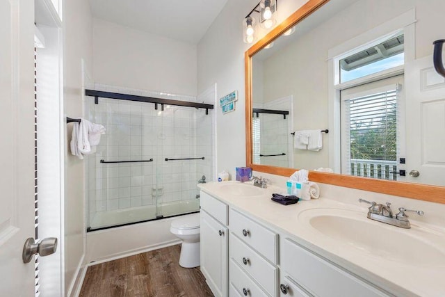 full bathroom featuring shower / bath combination with glass door, vanity, toilet, and wood-type flooring