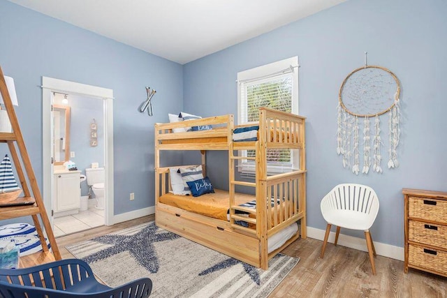 bedroom with connected bathroom and wood-type flooring